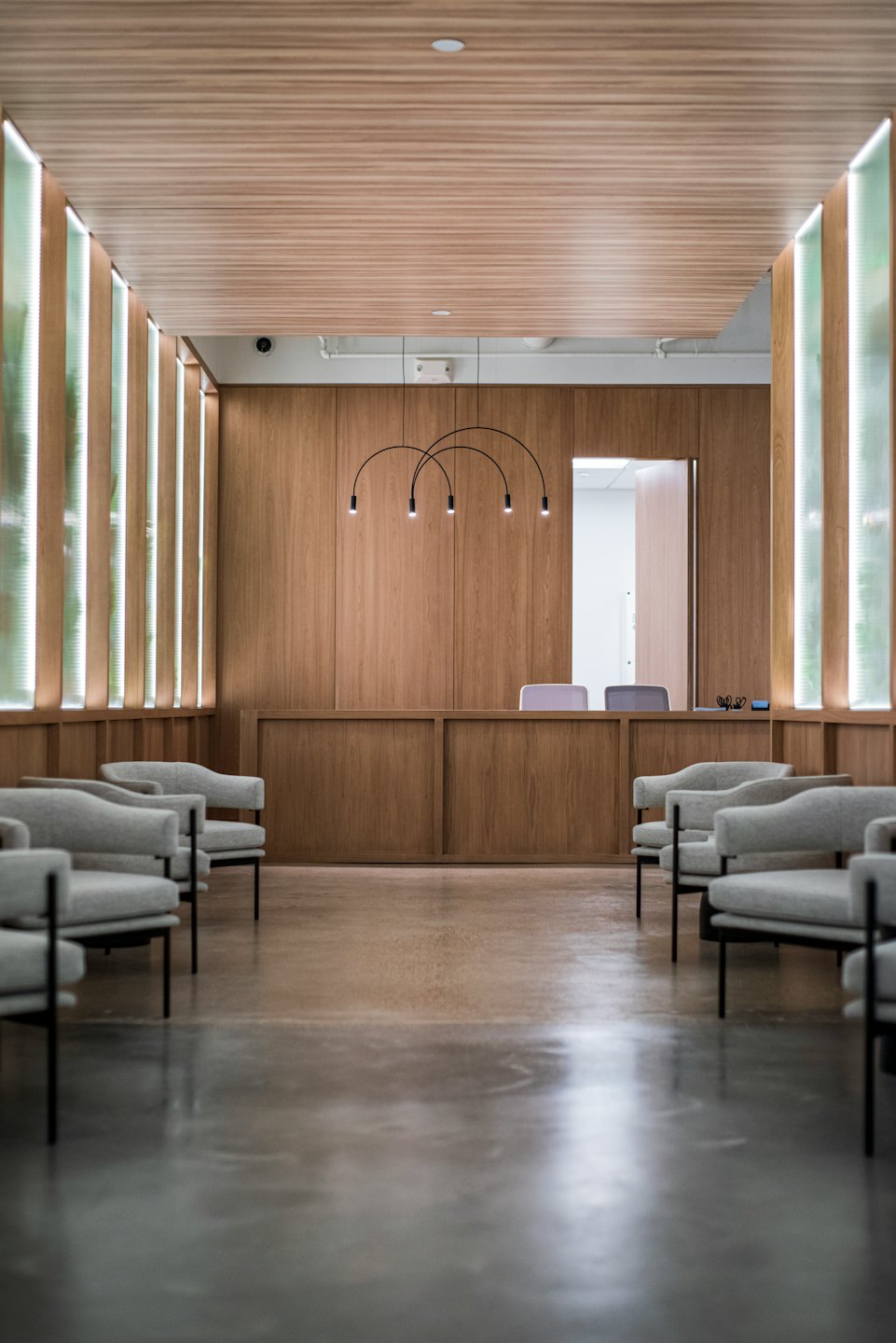 Sala de espera vacía con sillones grises y escritorio de recepción.