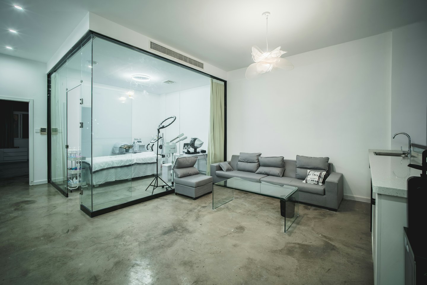 Sala de espera y sala de tratamiento de spa modernas con cama blanca.